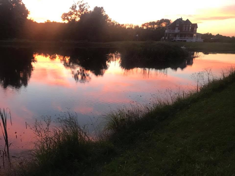 The Davis Farms farmhouse beside a pond at sunset